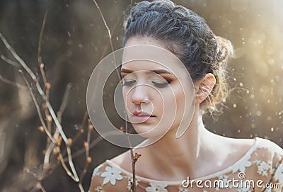 Atmospheric outdoor portrait of sensual young woman wearing elegant dress in a coniferous forest with rays of sunlight. Stock Photo