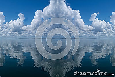 Atmospheric sky art image. White Cumulonimbus cloud in blue sky with ocean water reflections. Australia Stock Photo