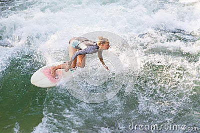 Atractive sporty girl surfing on famous artificial river wave in Englischer garten, Munich, Germany. Stock Photo