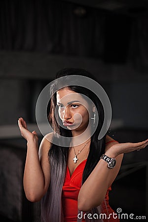 Atrractive brunette posing for camera with funny face. Womann in a red dress and with bright makeup. Stock Photo