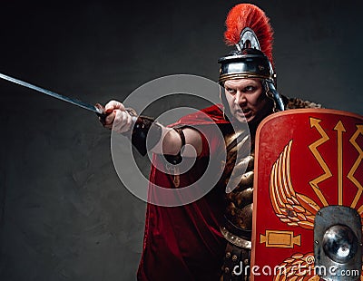 Angry roman soldier points sword against dark background Stock Photo