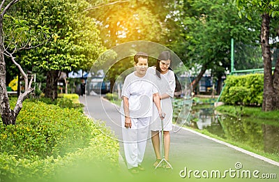 Attempt elderly asian woman walking to do workout with stick at public park,Daughter take care and support Stock Photo