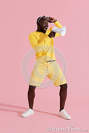 Attention! Black man shouting in megaphone on pink background Stock Photo