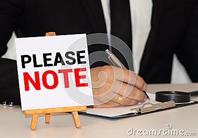 Attention please. word on white ring binder notebook with hand holding pencil on wood table Stock Photo