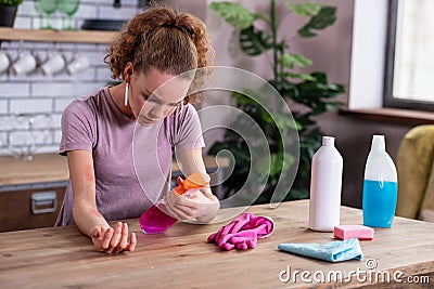 Attentive angry girl reading ingredients of cleaning spray Stock Photo