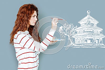Attentive artist holding a brush and painting a house Stock Photo