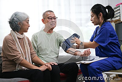 Attentive doctor or healthcare worker giving professional advice to senior couple during home visit Stock Photo