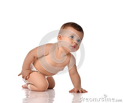 Attentive infant baby toddler in diaper stands on all fours touching his leg looking up trying to stand up Stock Photo