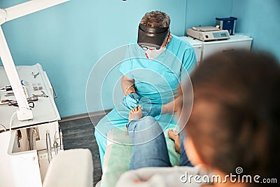 Professional chiropodist treating feet during medical procedure Stock Photo