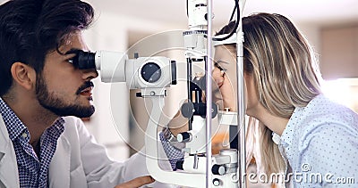 Attentive optometrist examining female patient on slit lamp Stock Photo