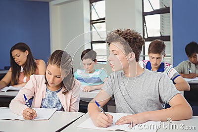 Attentive school kids doing homework in classroom Stock Photo
