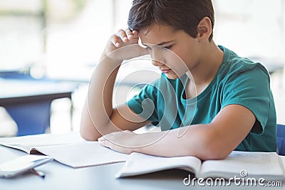 Attentive schoolboy studying in classroom Stock Photo