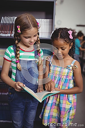 Attentive schoolgirls reading book in library Stock Photo