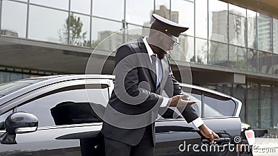 Attentive taxi driver politely opening car door, inviting client to sit down Stock Photo