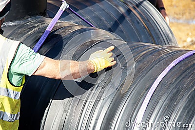 Attenuation tank made of big diameter plastic pipe delivered on construction site, offloaded and moved by an excavator into Stock Photo