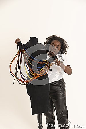Attractive African female and a tailors dummy. Arranging coloured necklaces for a display. Stock Photo