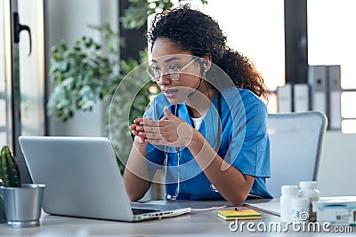 Attractive afro female doctor talking while explaining medical treatment to patient through a video call with laptop in the Stock Photo