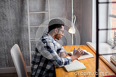 Attractive Afro student sitting at the table and preparing for exams Stock Photo