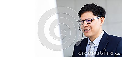 Attractive Asian Businessman work with phone, headset at call center and telemaketing sale support workplace. Customer service Stock Photo