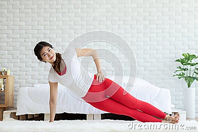 Attractive Asian woman practice yoga side plank pose to meditation in bedroom Stock Photo