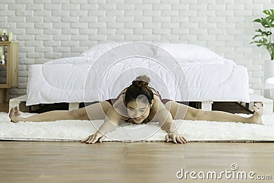 Attractive Asian woman practice yoga upavistha konasana or Seated angle pose to meditation in bedroom Stock Photo