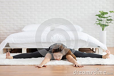 Attractive Asian woman practice yoga upavistha konasana or Seated angle pose to meditation in bedroom after wake up Stock Photo