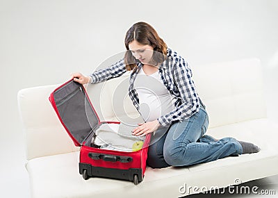 Attractive awaiting woman packing children's clothes into bag Stock Photo