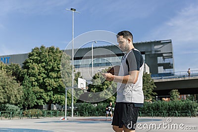 An attractive basketball player takes a break and looks at his mobile phone Stock Photo