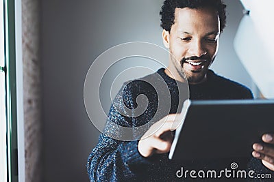 Attractive bearded African businessman using tablet while standing at his modern home office.Concept of young people Stock Photo