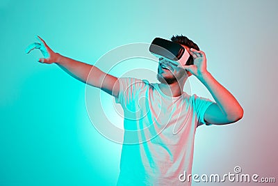 Attractive bearded man trying VR headset and poniting. Young man exploring another world with virtual reality goggles on Stock Photo