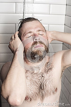 Bearded man washing her hair in the shower under running water. Stock Photo