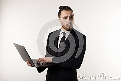 Attractive bearded middle manager wearing black suit and tie thinking with laptop in hands how to solve the problem Stock Photo