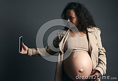 Attractive beautiful young gravid female, expectant mother photographing her tummy in third trimester of happy pregnancy Stock Photo