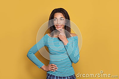 Attractive black woman thinking and smiling on brigt yellow background Stock Photo