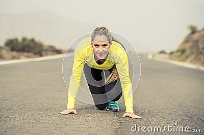 Attractive blond sport woman ready to start running practice training race starting on asphalt road mountain landscape Stock Photo