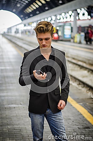 Attractive blond young man in station using cellphone Stock Photo