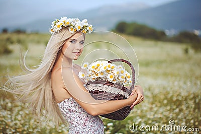 Attractive blonde in chamomile field. Young woman in wreath Stock Photo