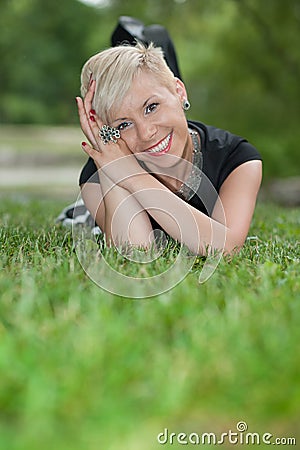 Attractive blonde girl posing in nature lying on grass Stock Photo