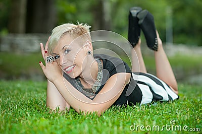 Attractive blonde girl posing in nature lying on grass Stock Photo