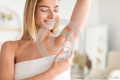 Attractive Blonde Woman Applying Antiperspirant Underarms In Modern Bathroom Stock Photo