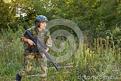 Attractive brave military woman with a gun in forest, survival in wild forest Stock Photo