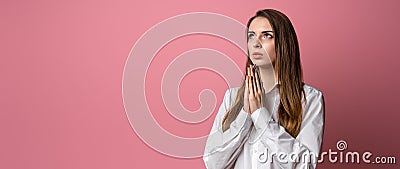 Attractive brunette girl prays for wellness of family keeps palms pressed together in praying gesture saying namaste Stock Photo