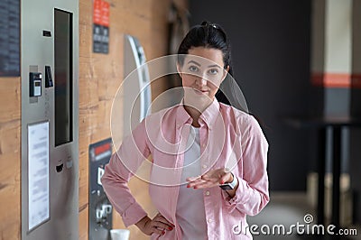 Brunette woman standing near automatic vending machine. Stock Photo