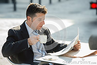 Attractive businessman sitting outdoors having coffee cup for breakfast early morning reading newspaper news looking relaxed Stock Photo