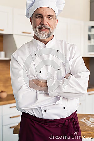 Attractive Caucasian chef standing with arms crossed in a restaurant kitchen Stock Photo