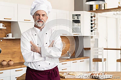 Attractive Caucasian chef standing with arms crossed in a restaurant kitchen Stock Photo