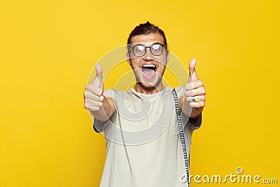 Attractive caucasian man smiling and showing thumb up gesture with both hands over yellow background and looking at camera. Stock Photo