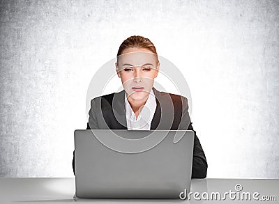 Attractive concentrated business woman is sitting at workplace in front of the laptop, leaning on the desk and wondering about Stock Photo
