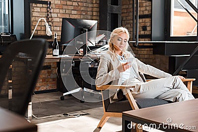 Attractive concentrated businesswoman sitting in armchair Stock Photo