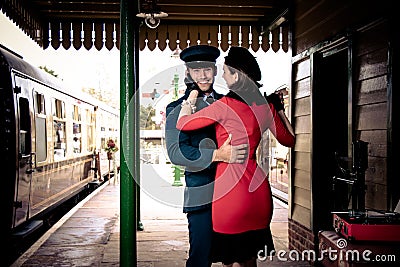 Attractive couple dance on railway station platform with portable record player Stock Photo